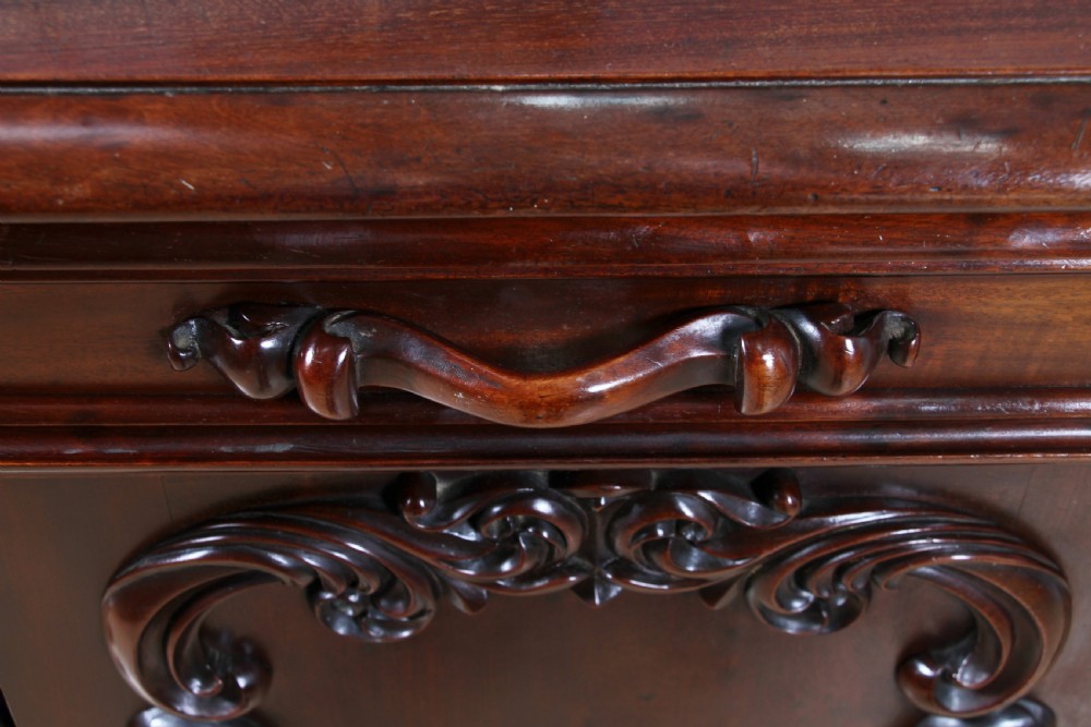 A 19th-century dark mahogany chiffonier featuring two top drawers, two carved panel cupboard doors, barley twist side columns, and a carved scroll splashback. View XII