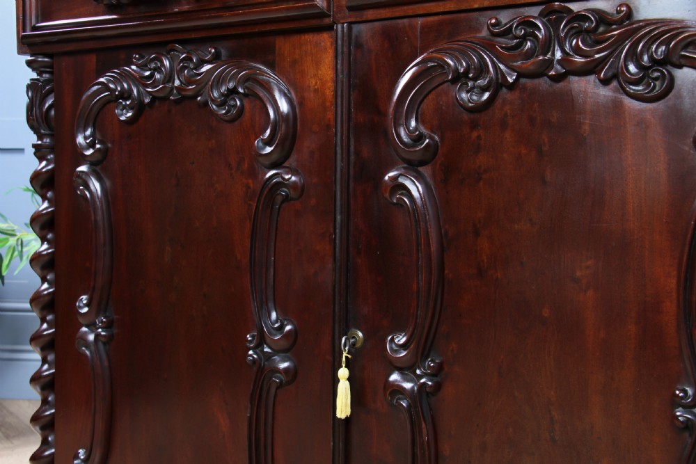 A 19th-century dark mahogany chiffonier featuring two top drawers, two carved panel cupboard doors, barley twist side columns, and a carved scroll splashback. View XIII