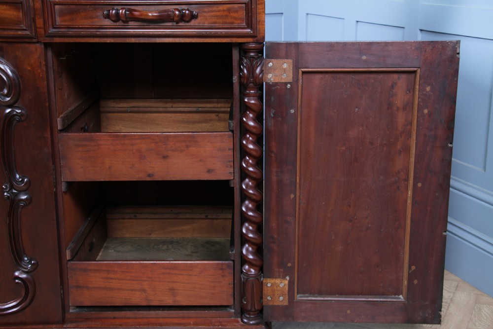 A 19th-century dark mahogany chiffonier featuring two top drawers, two carved panel cupboard doors, barley twist side columns, and a carved scroll splashback. View XIV