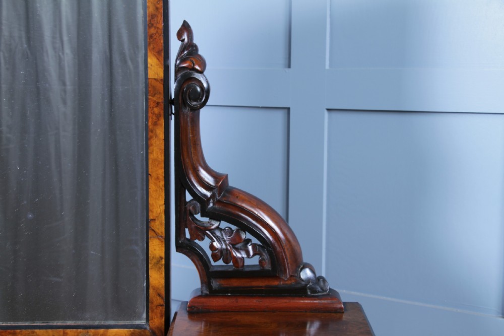 An antique Victorian burr walnut duchess dressing table featuring an integrated swing mirror, jewellery drawers, a curved piano top lid, turned front legs, and a plinth base. View VIII