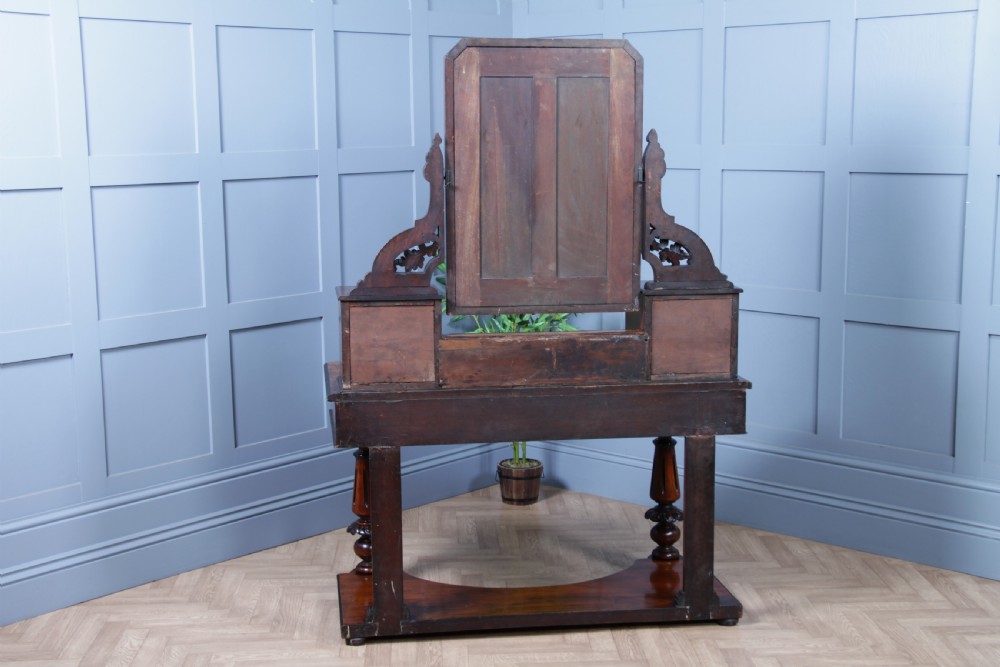 An antique Victorian burr walnut duchess dressing table featuring an integrated swing mirror, jewellery drawers, a curved piano top lid, turned front legs, and a plinth base. View XX