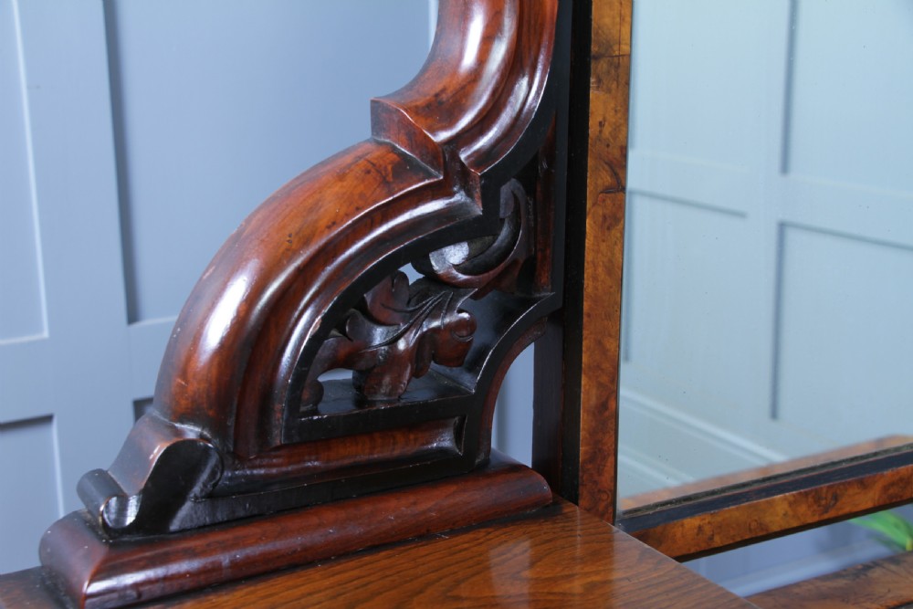 An antique Victorian burr walnut duchess dressing table featuring an integrated swing mirror, jewellery drawers, a curved piano top lid, turned front legs, and a plinth base. View XXIV