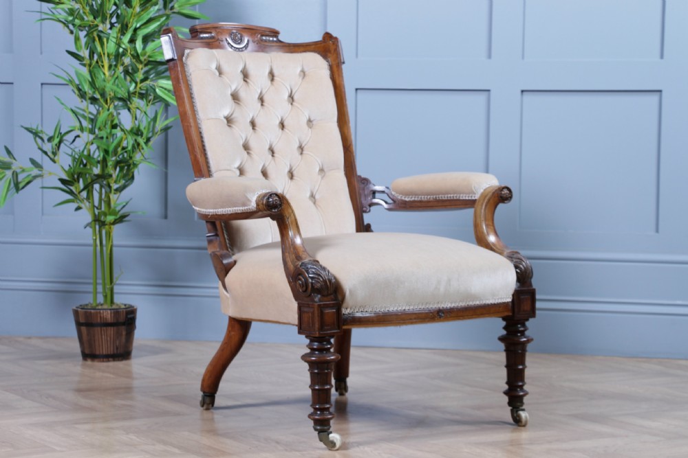 A Victorian carved walnut two-piece salon suite comprising a button-tufted cream velvet sofa and a matching armchair on turned legs with castors. View V