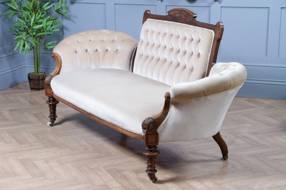 A Victorian carved walnut two-piece salon suite comprising a button-tufted cream velvet sofa and a matching armchair on turned legs with castors. View XII