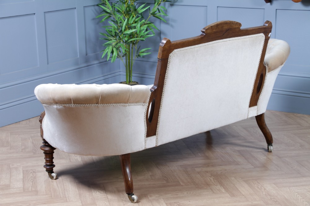 A Victorian carved walnut two-piece salon suite comprising a button-tufted cream velvet sofa and a matching armchair on turned legs with castors. View XVI