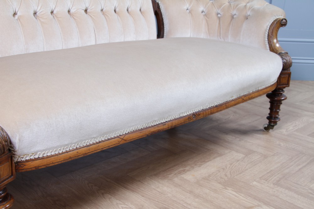 A Victorian carved walnut two-piece salon suite comprising a button-tufted cream velvet sofa and a matching armchair on turned legs with castors. View XVII