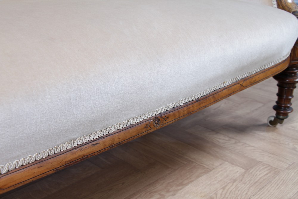 A Victorian carved walnut two-piece salon suite comprising a button-tufted cream velvet sofa and a matching armchair on turned legs with castors. View XVIII