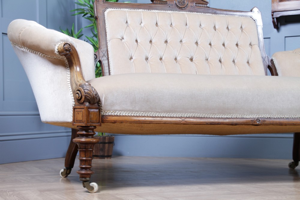 A Victorian carved walnut two-piece salon suite comprising a button-tufted cream velvet sofa and a matching armchair on turned legs with castors. View XIX