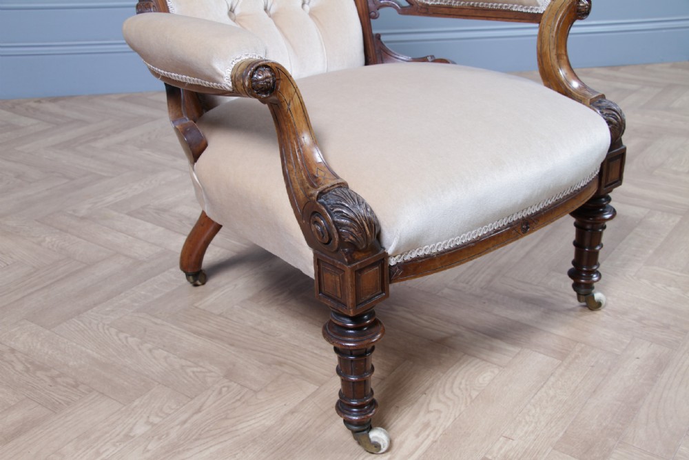 A Victorian carved walnut two-piece salon suite comprising a button-tufted cream velvet sofa and a matching armchair on turned legs with castors. View XXIV