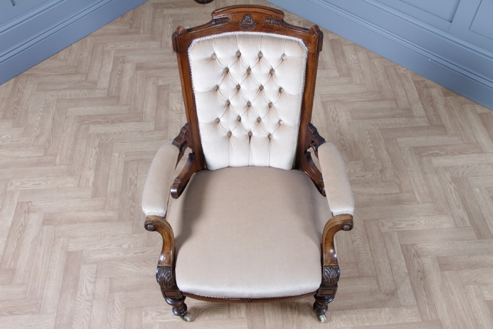 A Victorian carved walnut two-piece salon suite comprising a button-tufted cream velvet sofa and a matching armchair on turned legs with castors. View XXV