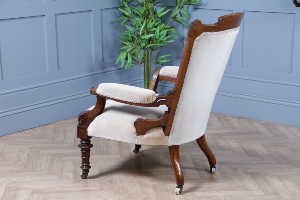 A Victorian carved walnut two-piece salon suite comprising a button-tufted cream velvet sofa and a matching armchair on turned legs with castors. View XXVIII