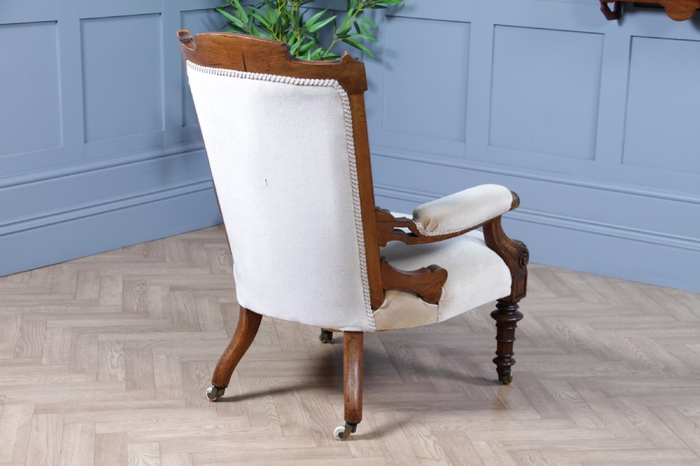 A Victorian carved walnut two-piece salon suite comprising a button-tufted cream velvet sofa and a matching armchair on turned legs with castors. View XXIX