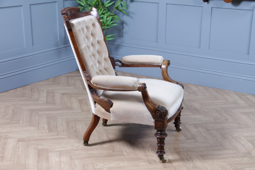 A Victorian carved walnut two-piece salon suite comprising a button-tufted cream velvet sofa and a matching armchair on turned legs with castors. View XXX
