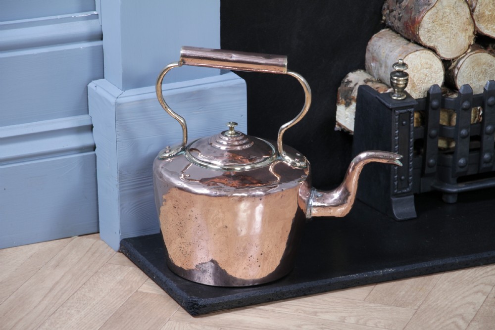 A polished George III copper kettle with a raised brass fixed handle and a curved gooseneck spout. View II