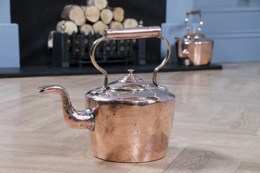 A polished George III copper kettle with a raised brass fixed handle and a curved gooseneck spout. View XIV