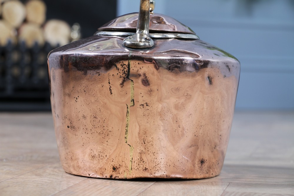 An antique George III polished copper kettle featuring a brass finial lid, overhead handle, and curved spout. View IX