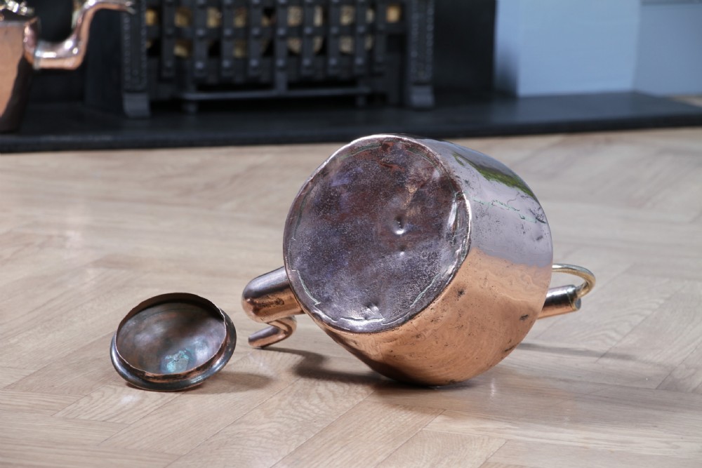 An antique George III polished copper kettle featuring a brass finial lid, overhead handle, and curved spout. View X
