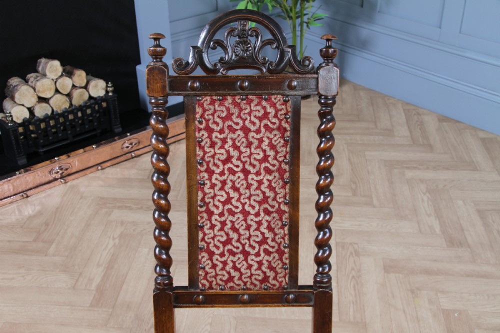 Late Victorian dark wood folding chair featuring barley twist uprights, a carved crest rail, red patterned upholstery, and brass stud trim. View XII