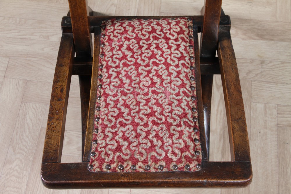 Late Victorian dark wood folding chair featuring barley twist uprights, a carved crest rail, red patterned upholstery, and brass stud trim. View XIII