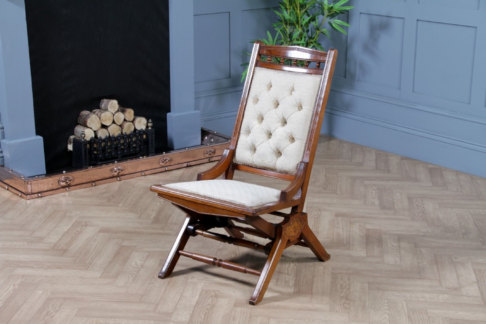 An Edwardian walnut platform rocking chair featuring cream button-backed upholstery and turned wooden spindles on a stationary crossed base. View II