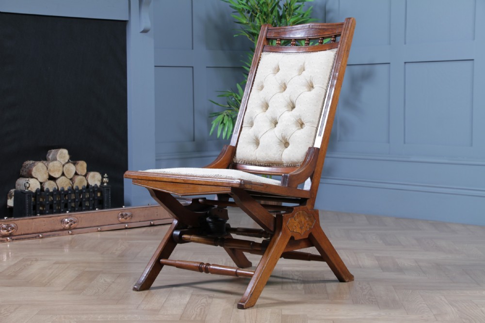 An Edwardian walnut platform rocking chair featuring cream button-backed upholstery and turned wooden spindles on a stationary crossed base. View III
