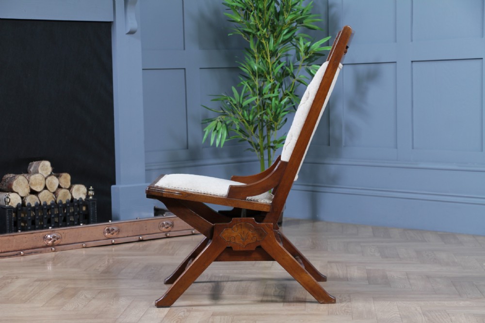 An Edwardian walnut platform rocking chair featuring cream button-backed upholstery and turned wooden spindles on a stationary crossed base. View IV