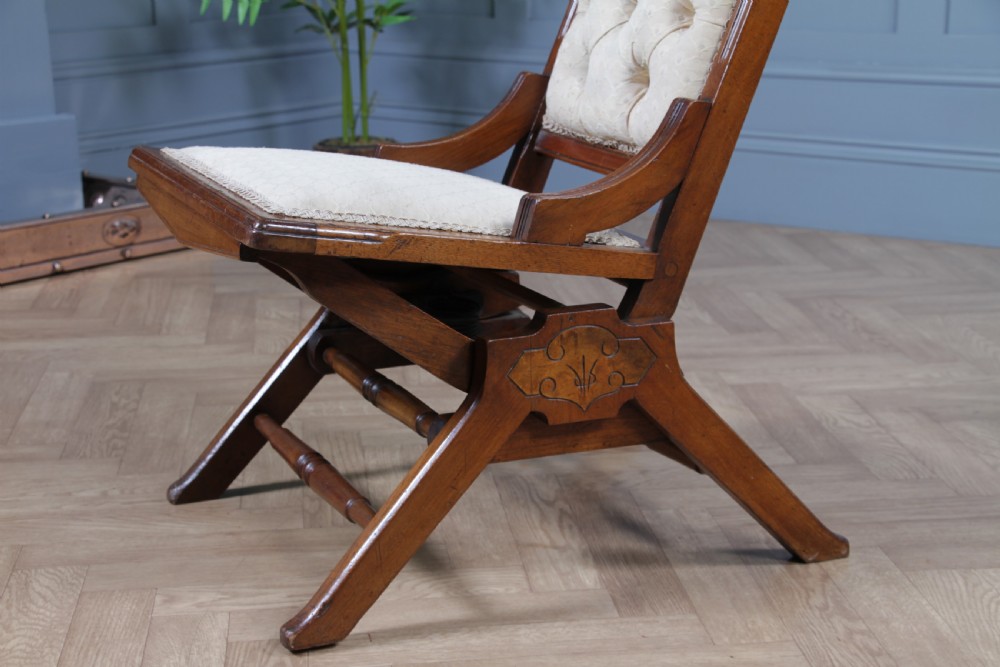 An Edwardian walnut platform rocking chair featuring cream button-backed upholstery and turned wooden spindles on a stationary crossed base. View V