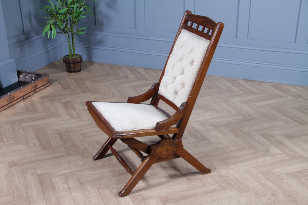 An Edwardian walnut platform rocking chair featuring cream button-backed upholstery and turned wooden spindles on a stationary crossed base. View VI