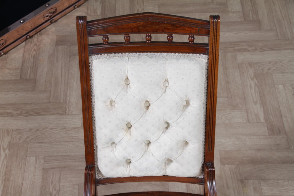 An Edwardian walnut platform rocking chair featuring cream button-backed upholstery and turned wooden spindles on a stationary crossed base. View VII