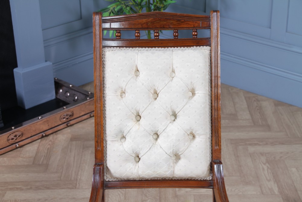 An Edwardian walnut platform rocking chair featuring cream button-backed upholstery and turned wooden spindles on a stationary crossed base. View VIII