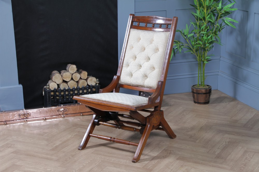 An Edwardian walnut platform rocking chair featuring cream button-backed upholstery and turned wooden spindles on a stationary crossed base. View XIV