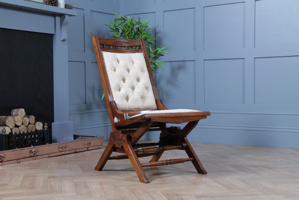 An Edwardian walnut platform rocking chair featuring cream button-backed upholstery and turned wooden spindles on a stationary crossed base. View XV