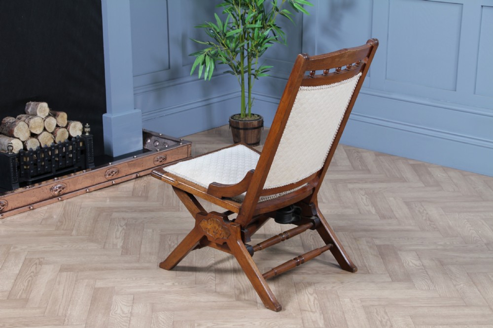 An Edwardian walnut platform rocking chair featuring cream button-backed upholstery and turned wooden spindles on a stationary crossed base. View XVII