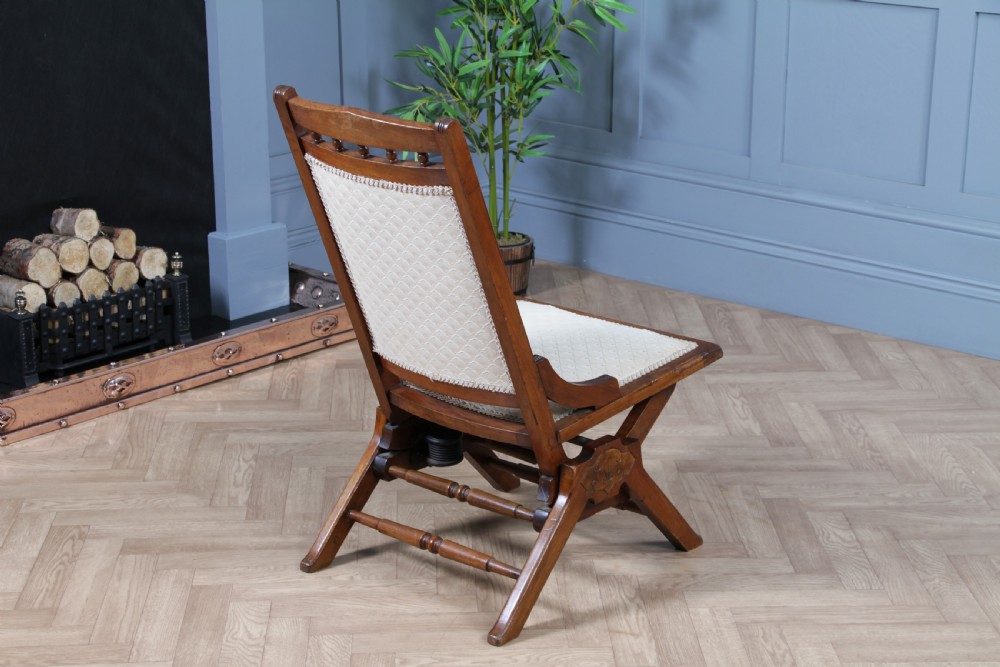 An Edwardian walnut platform rocking chair featuring cream button-backed upholstery and turned wooden spindles on a stationary crossed base. View XVIII