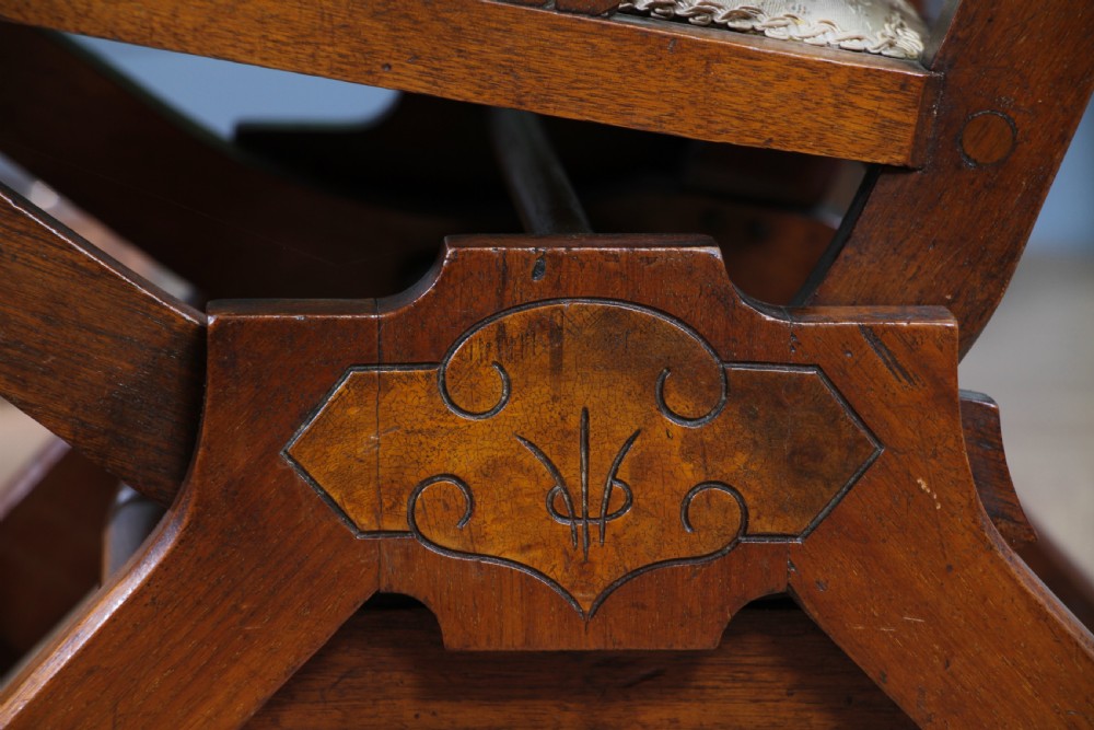 An Edwardian walnut platform rocking chair featuring cream button-backed upholstery and turned wooden spindles on a stationary crossed base. View XXI