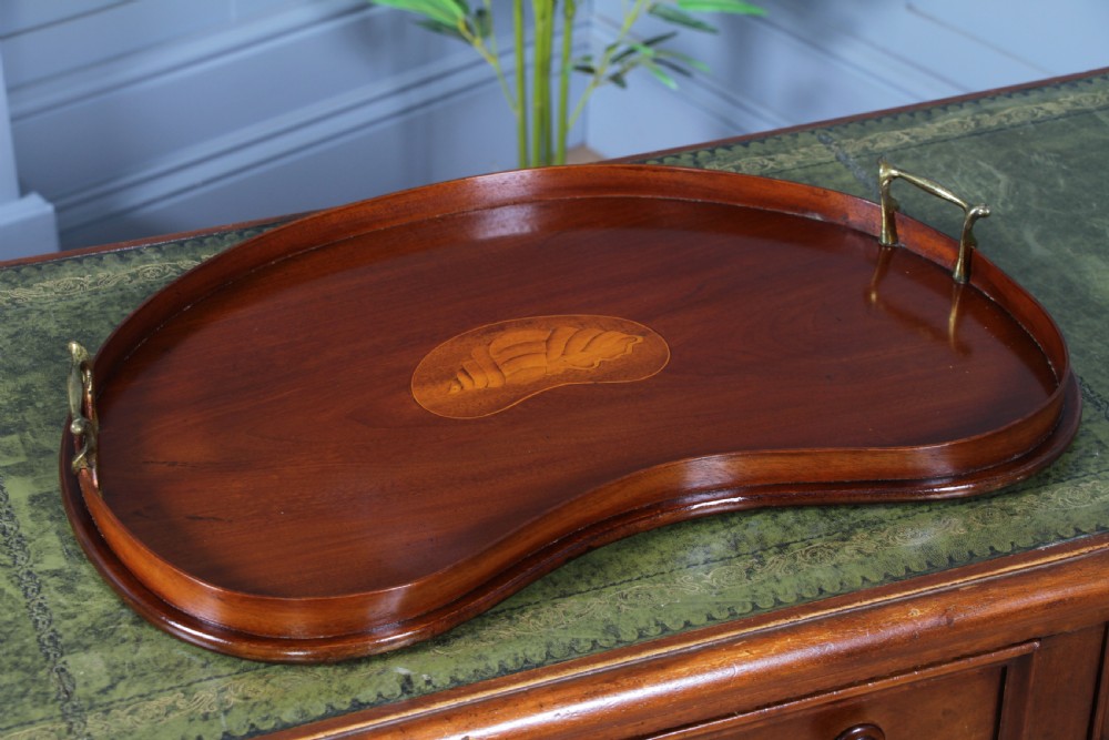 An Edwardian kidney-shaped solid mahogany serving tray featuring a central inlaid shell motif and two brass carrying handles. View II
