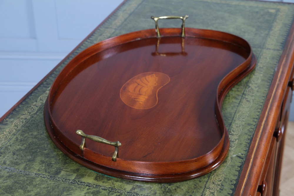 An Edwardian kidney-shaped solid mahogany serving tray featuring a central inlaid shell motif and two brass carrying handles. View VI