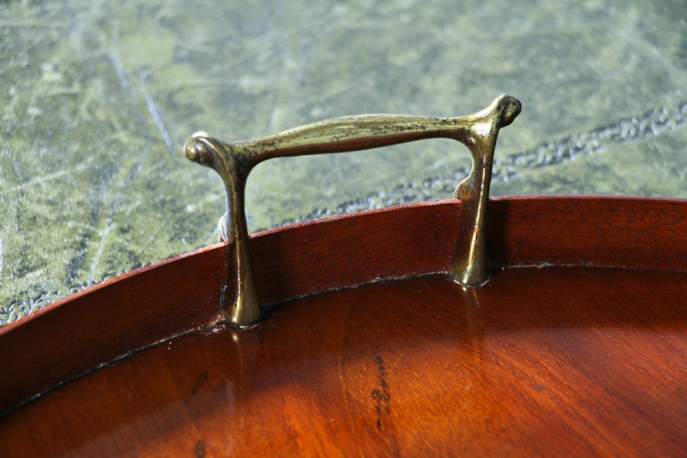 An Edwardian kidney-shaped solid mahogany serving tray featuring a central inlaid shell motif and two brass carrying handles. View X
