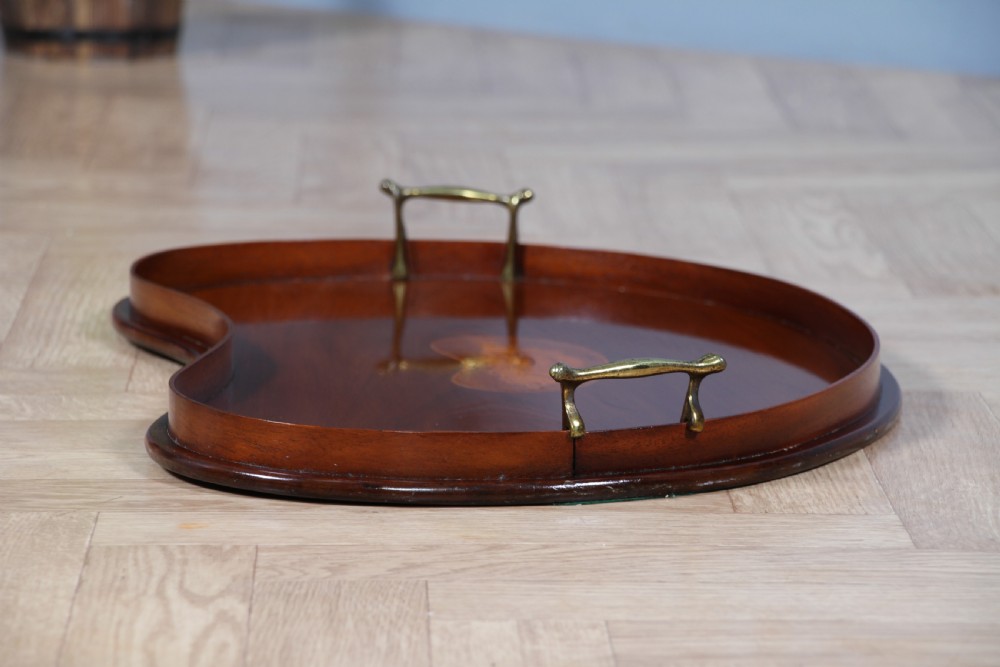An Edwardian kidney-shaped solid mahogany serving tray featuring a central inlaid shell motif and two brass carrying handles. View XIII