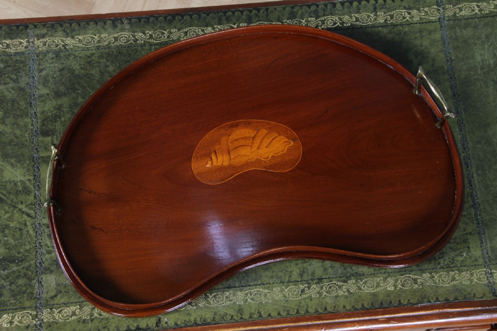 An Edwardian kidney-shaped solid mahogany serving tray featuring a central inlaid shell motif and two brass carrying handles. View XV