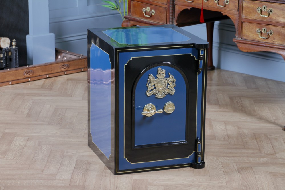 A heavy restored Victorian cast iron safe featuring a deep blue and black lacquered exterior with gold pinstriping and a brass royal coat of arms crest. View II