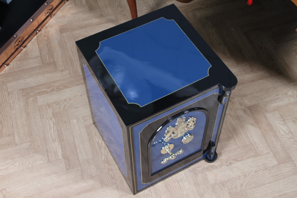 A heavy restored Victorian cast iron safe featuring a deep blue and black lacquered exterior with gold pinstriping and a brass royal coat of arms crest. View V