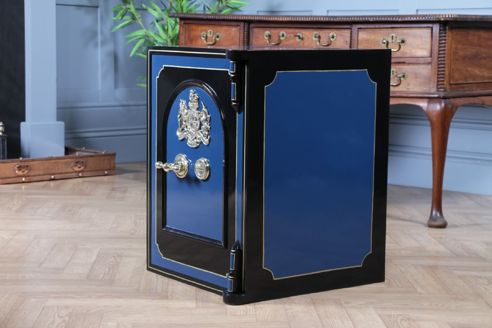 A heavy restored Victorian cast iron safe featuring a deep blue and black lacquered exterior with gold pinstriping and a brass royal coat of arms crest. View IX