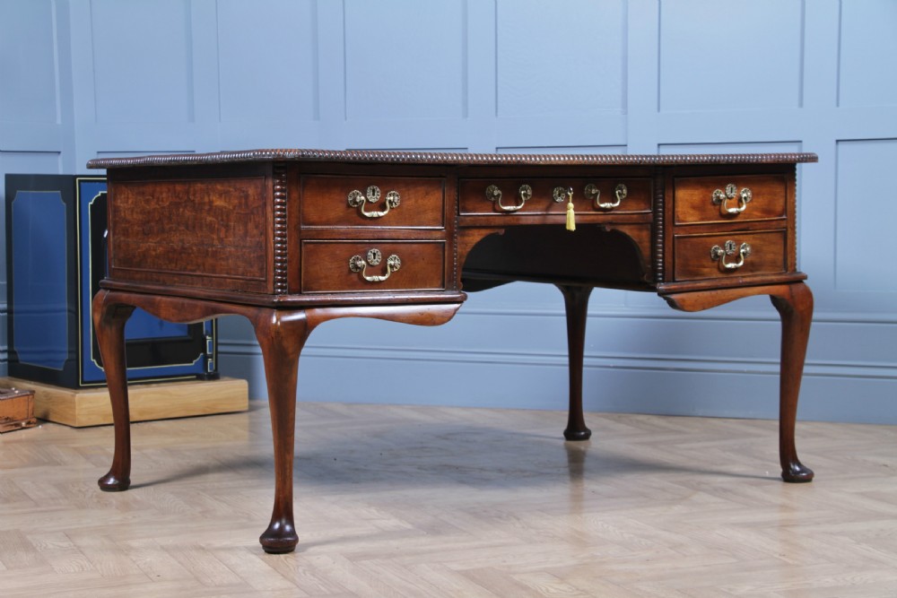 A Georgian mahogany writing desk featuring a rectangular top, central kneehole drawer flanked by side drawers, polished brass handles, and cabriole legs ending in pad feet. View II