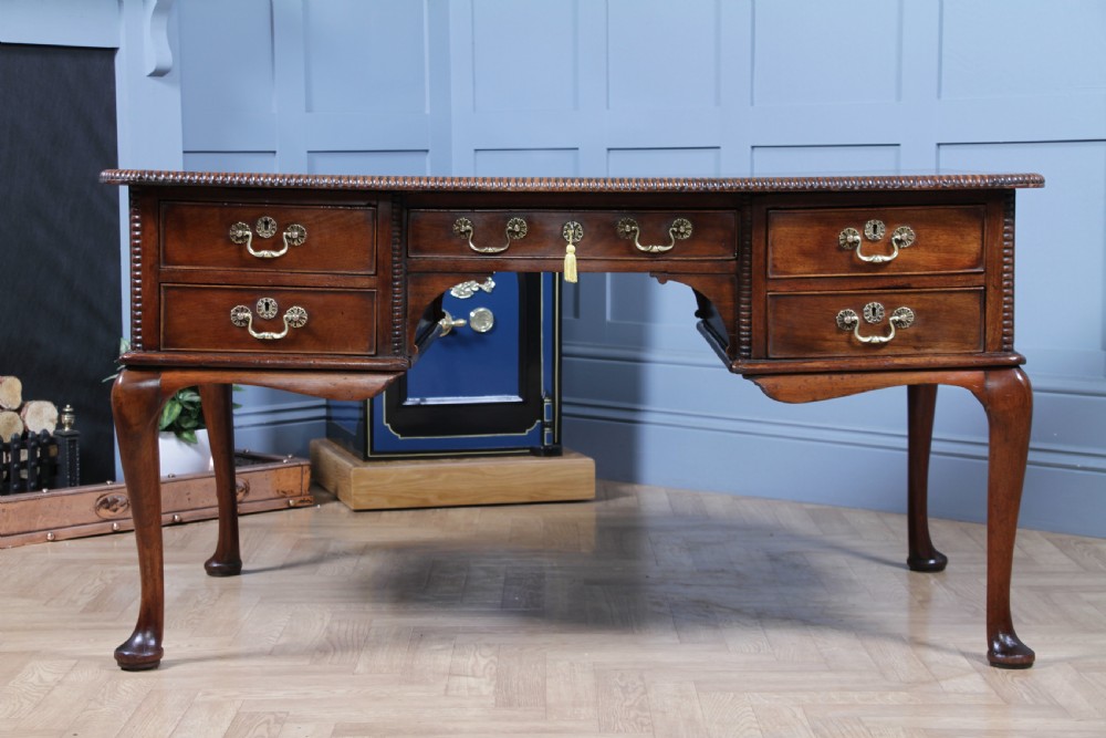 A Georgian mahogany writing desk featuring a rectangular top, central kneehole drawer flanked by side drawers, polished brass handles, and cabriole legs ending in pad feet. View V