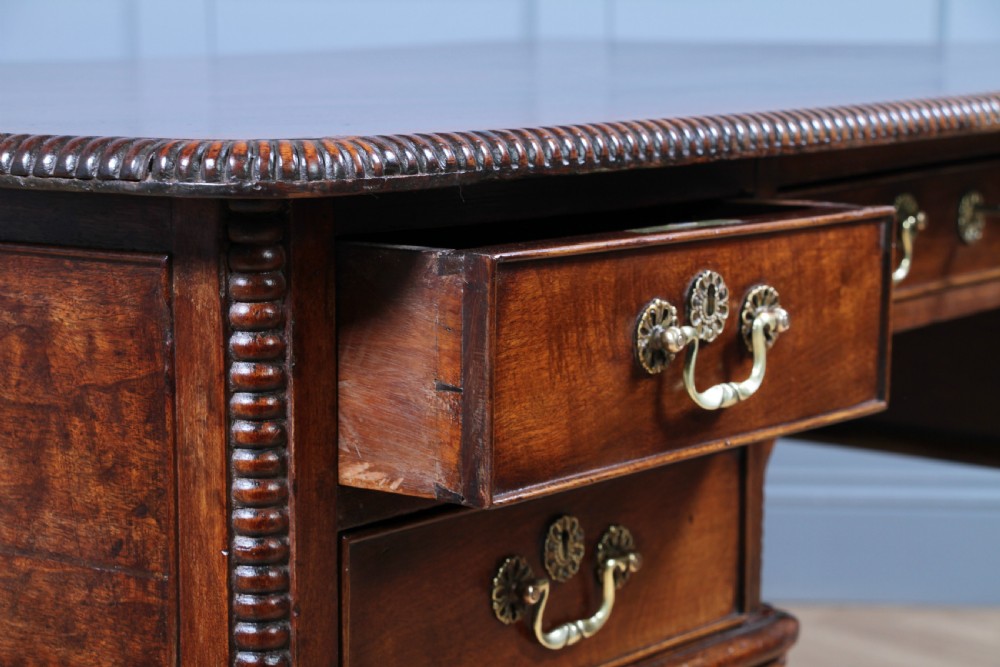 A Georgian mahogany writing desk featuring a rectangular top, central kneehole drawer flanked by side drawers, polished brass handles, and cabriole legs ending in pad feet. View VII