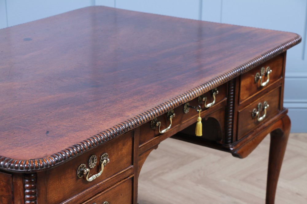 A Georgian mahogany writing desk featuring a rectangular top, central kneehole drawer flanked by side drawers, polished brass handles, and cabriole legs ending in pad feet. View VIII