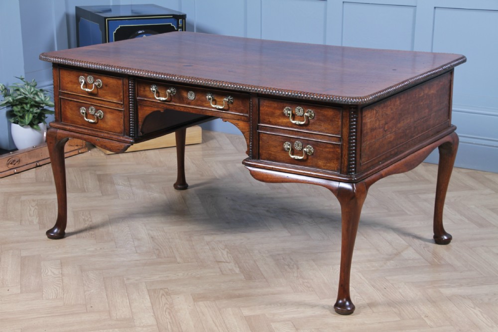 A Georgian mahogany writing desk featuring a rectangular top, central kneehole drawer flanked by side drawers, polished brass handles, and cabriole legs ending in pad feet. View IX
