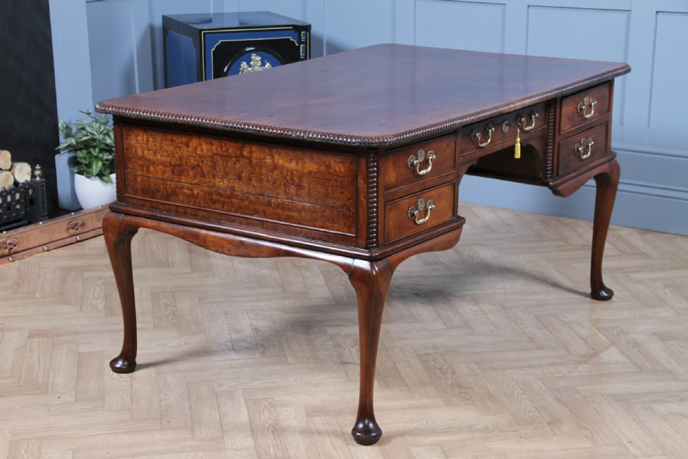 A Georgian mahogany writing desk featuring a rectangular top, central kneehole drawer flanked by side drawers, polished brass handles, and cabriole legs ending in pad feet. View X