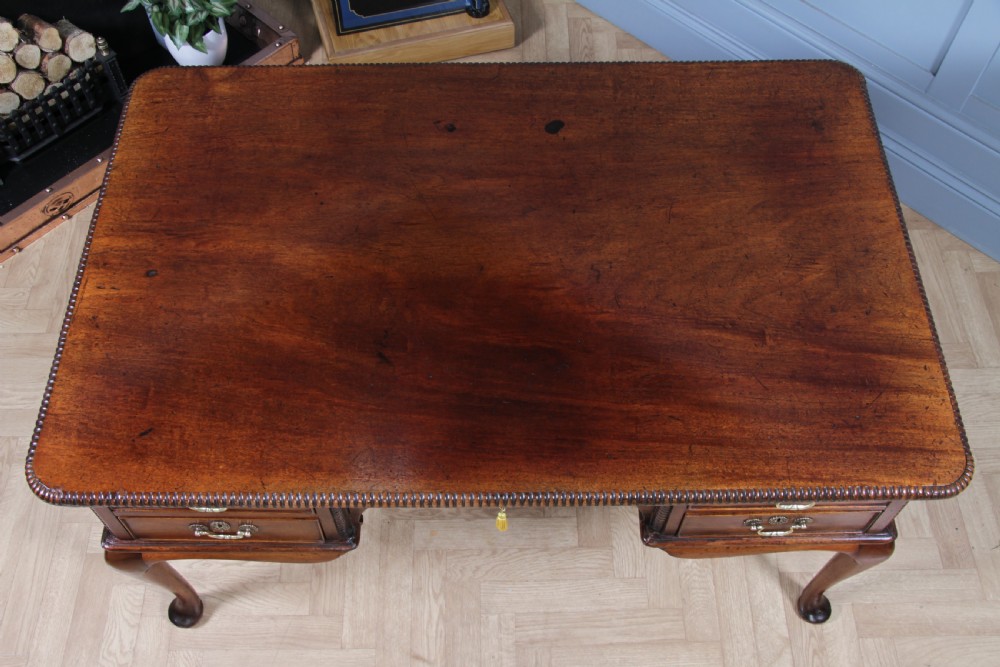 A Georgian mahogany writing desk featuring a rectangular top, central kneehole drawer flanked by side drawers, polished brass handles, and cabriole legs ending in pad feet. View XI